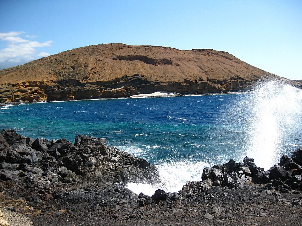 The bay below Montaña Amarilla, with spray from the blowhole on the right