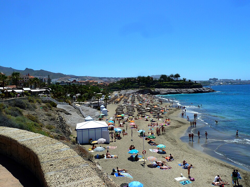 Playa del Duque with its parasols and beach huts, seen from the north end